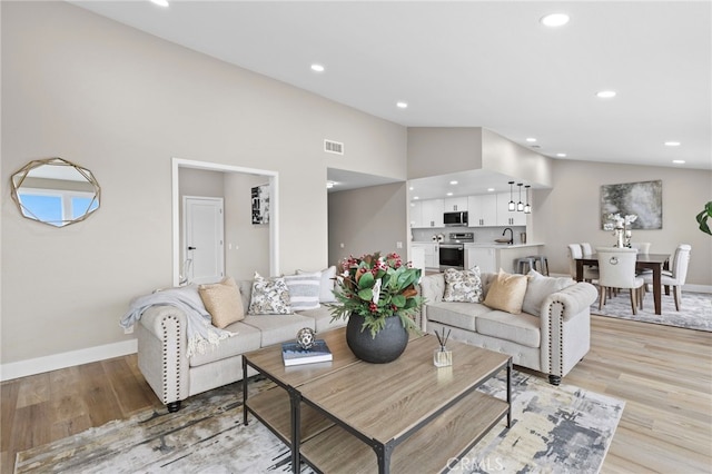 living room with high vaulted ceiling and light hardwood / wood-style floors