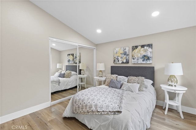 bedroom with hardwood / wood-style flooring, vaulted ceiling, and a closet