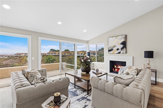 living room featuring lofted ceiling, hardwood / wood-style floors, and a high end fireplace