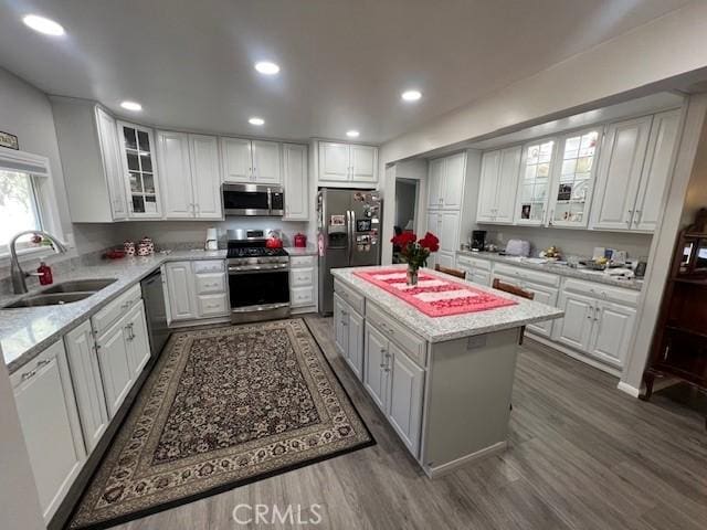 kitchen featuring stainless steel appliances, a sink, white cabinetry, and a center island