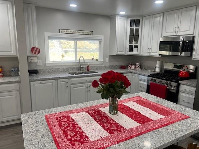 kitchen with appliances with stainless steel finishes, white cabinets, a sink, and recessed lighting