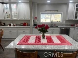 kitchen featuring black dishwasher, glass insert cabinets, white cabinets, a kitchen island, and a sink