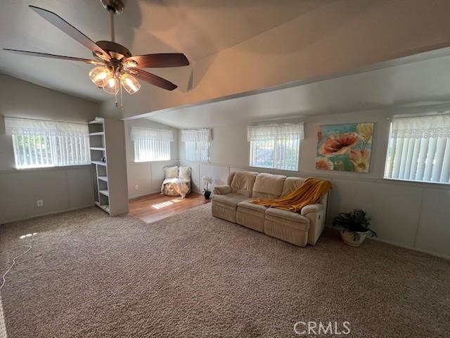 carpeted living area featuring lofted ceiling and a ceiling fan