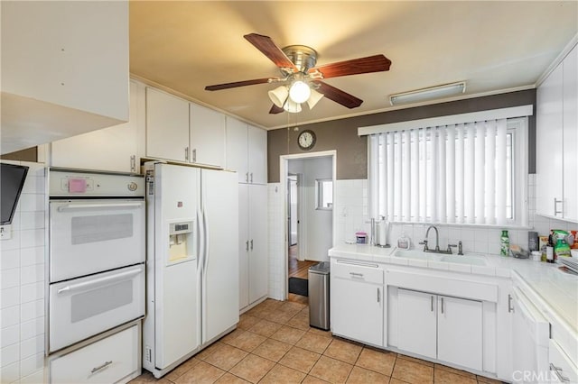 kitchen with sink, tile countertops, white cabinets, and white appliances