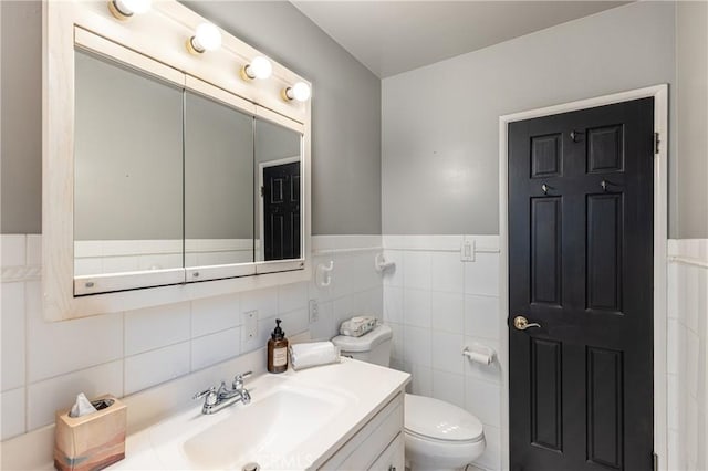 bathroom featuring vanity, tile walls, and toilet