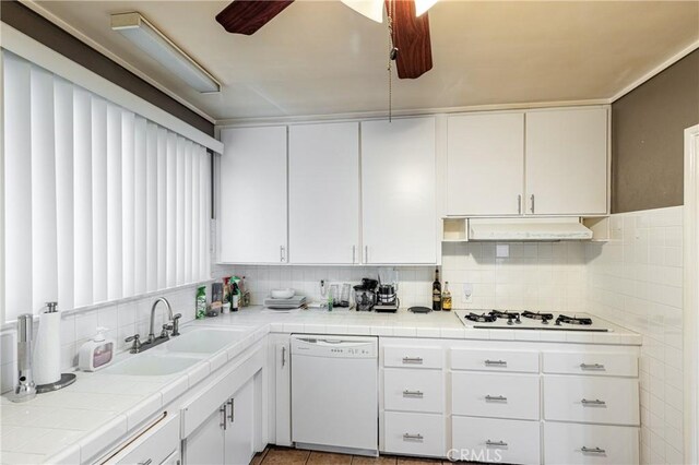 kitchen with white appliances, tile counters, sink, and white cabinets