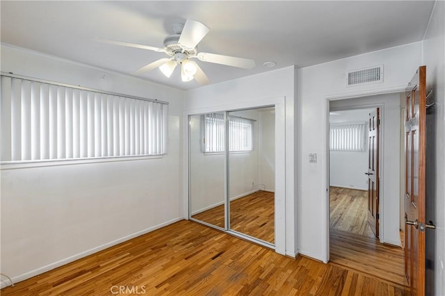 unfurnished bedroom with hardwood / wood-style flooring, ceiling fan, and a closet