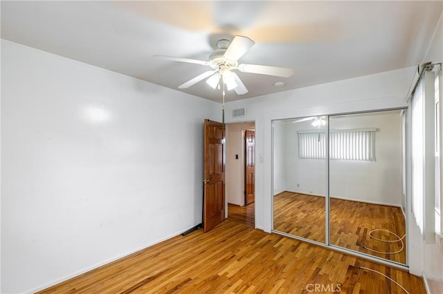 unfurnished bedroom featuring ceiling fan, a closet, and light hardwood / wood-style flooring