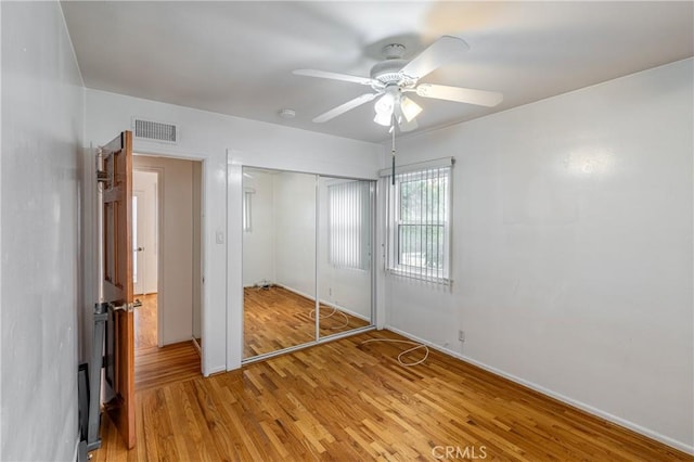 unfurnished bedroom with ceiling fan, light wood-type flooring, and a closet