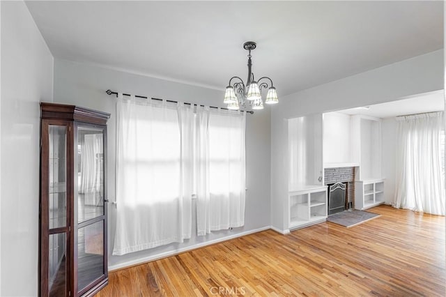 interior space with a brick fireplace, a notable chandelier, and light hardwood / wood-style flooring