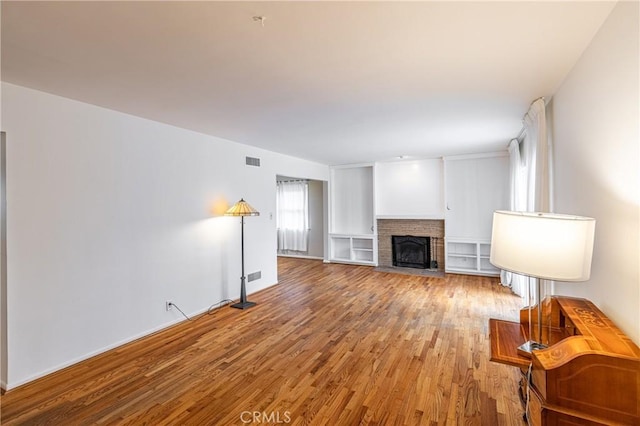 living room featuring a brick fireplace and light hardwood / wood-style flooring