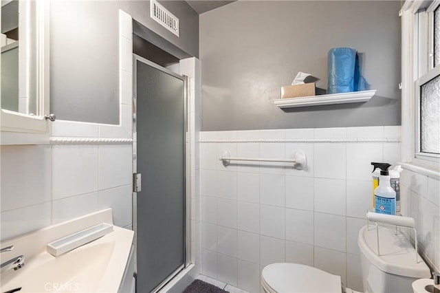 bathroom with tile walls, toilet, and walk in shower