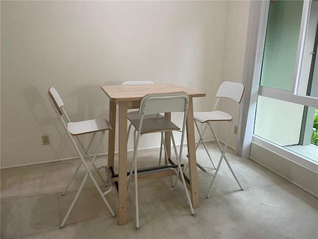 dining space featuring light carpet and baseboards