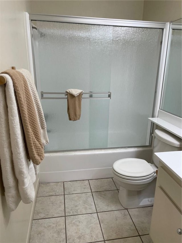 bathroom with combined bath / shower with glass door, vanity, toilet, and tile patterned floors