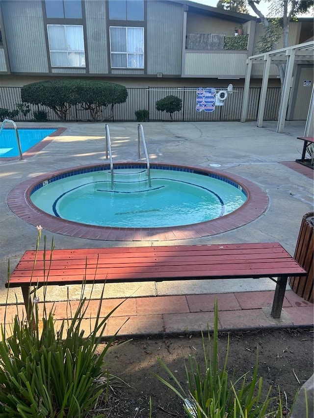 view of swimming pool featuring a hot tub, fence, and a patio