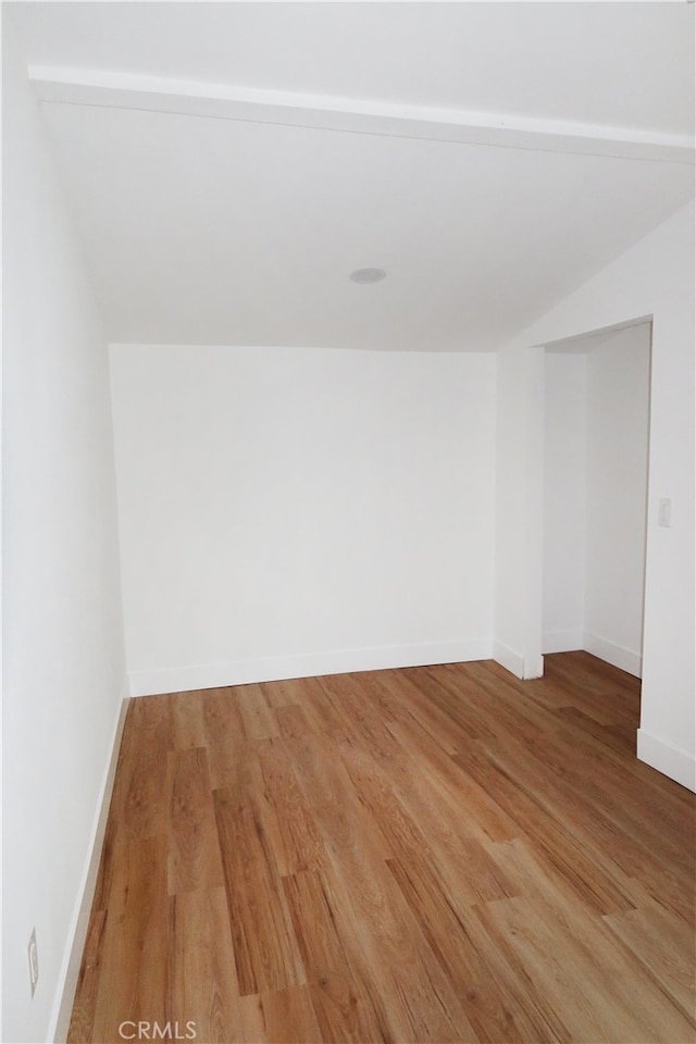 empty room with wood-type flooring and vaulted ceiling