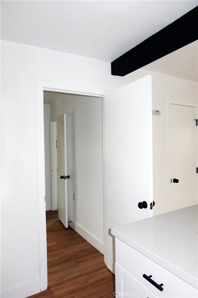 hall with dark hardwood / wood-style floors and beam ceiling