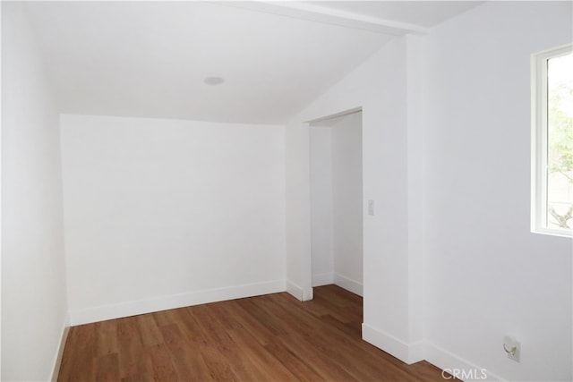 empty room with plenty of natural light, lofted ceiling, and dark hardwood / wood-style flooring