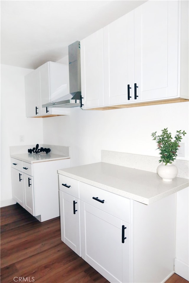 interior space with wall chimney range hood, white cabinets, and dark hardwood / wood-style flooring