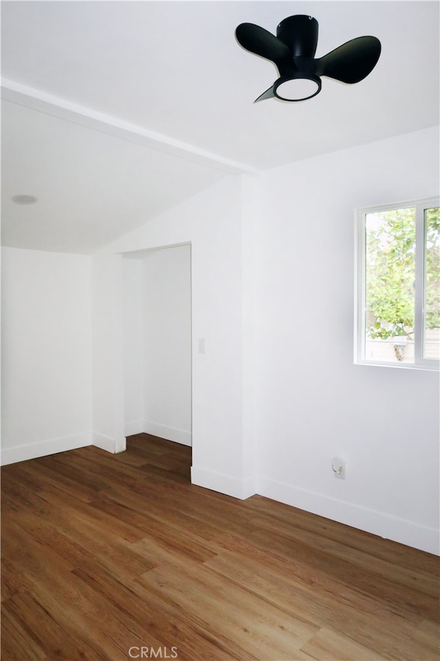 empty room with dark hardwood / wood-style flooring, lofted ceiling, and ceiling fan