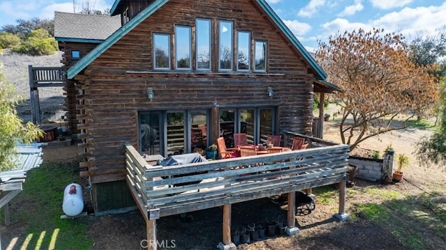 back of house with log siding and a deck