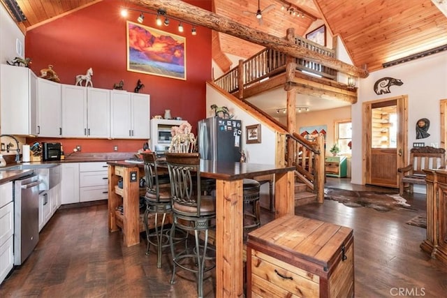 kitchen featuring dark countertops, wood ceiling, white cabinetry, and stainless steel appliances