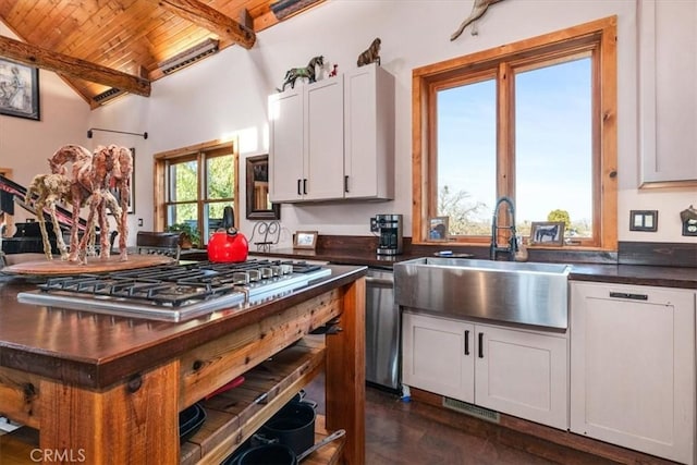 kitchen with wooden ceiling, a sink, white cabinetry, dark countertops, and stainless steel gas stovetop