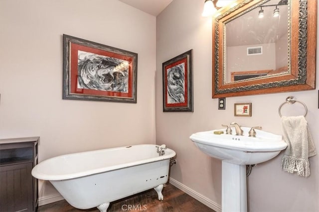 bathroom with a freestanding bath, wood finished floors, visible vents, and baseboards