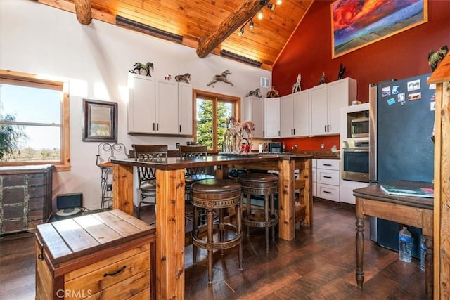 kitchen with a breakfast bar, wood ceiling, white cabinets, appliances with stainless steel finishes, and dark countertops