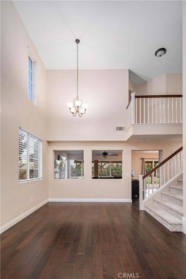 unfurnished living room featuring dark hardwood / wood-style floors, a high ceiling, and a notable chandelier