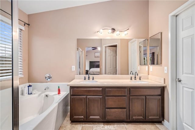 bathroom with ceiling fan, vanity, tile patterned flooring, and tiled tub