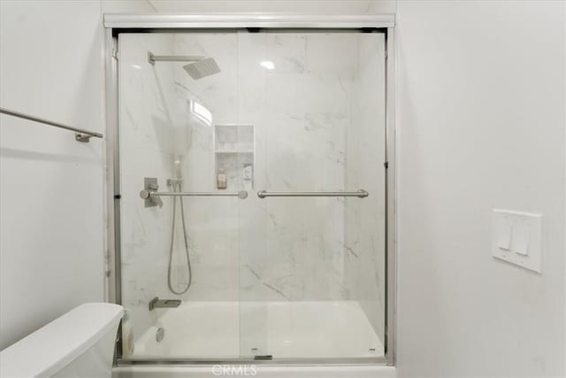 bathroom with toilet and combined bath / shower with glass door