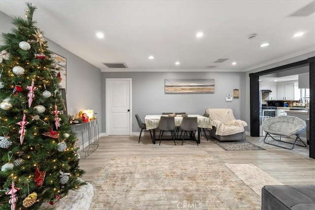 living room with crown molding and light hardwood / wood-style floors