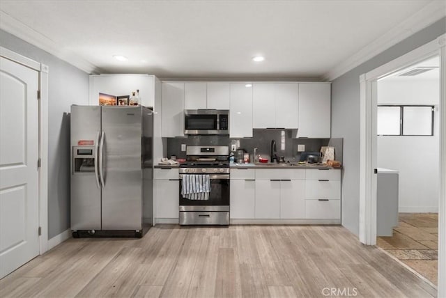 kitchen featuring sink, white cabinetry, stainless steel appliances, light hardwood / wood-style floors, and decorative backsplash