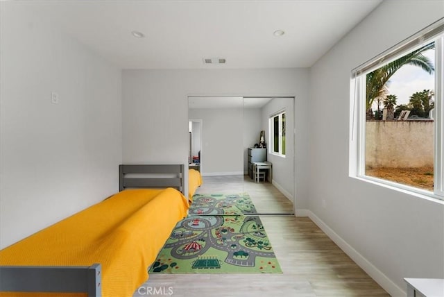 bedroom with light hardwood / wood-style floors and a closet