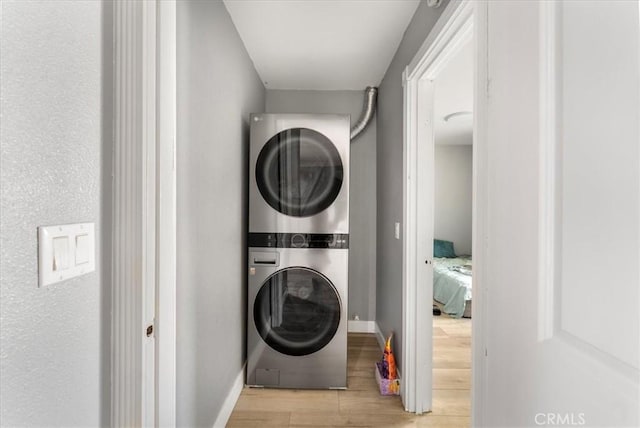 washroom with stacked washer and dryer and light hardwood / wood-style flooring