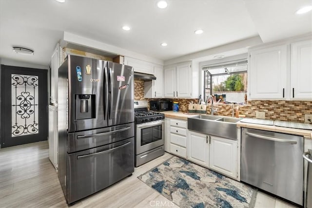 kitchen with sink, white cabinetry, tasteful backsplash, light hardwood / wood-style flooring, and appliances with stainless steel finishes