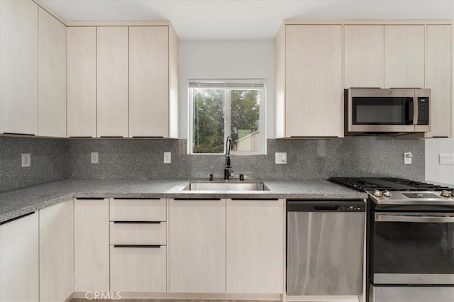 kitchen with appliances with stainless steel finishes, sink, cream cabinets, and decorative backsplash