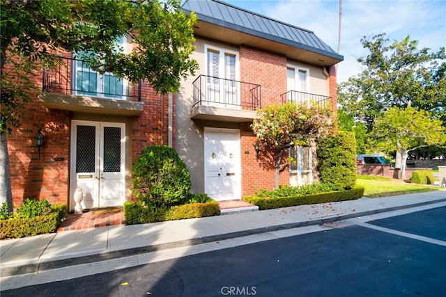 view of property with a balcony and french doors