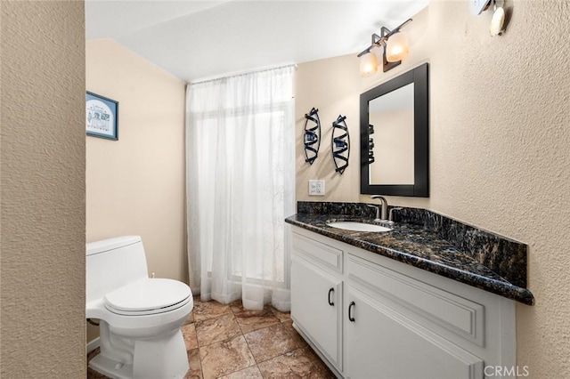 bathroom with vanity, vaulted ceiling, and toilet