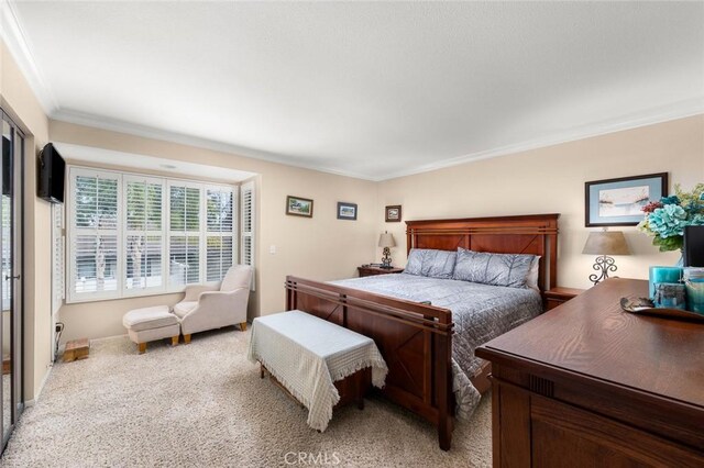 bedroom with ornamental molding and light carpet