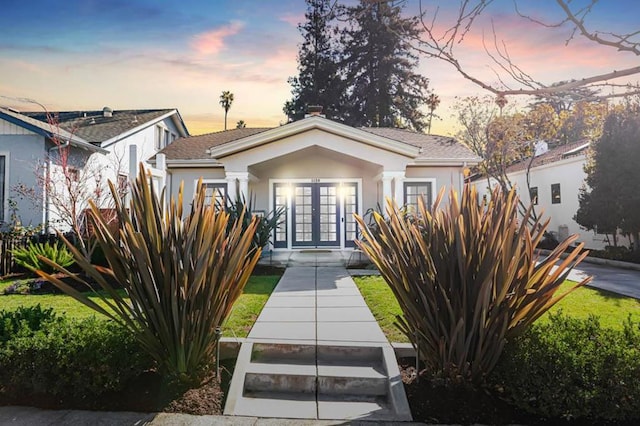 bungalow-style home with a yard and french doors