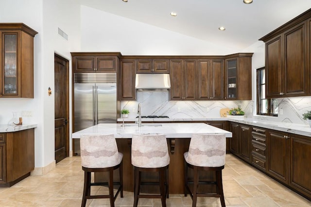 kitchen with dark brown cabinetry, sink, vaulted ceiling, and an island with sink