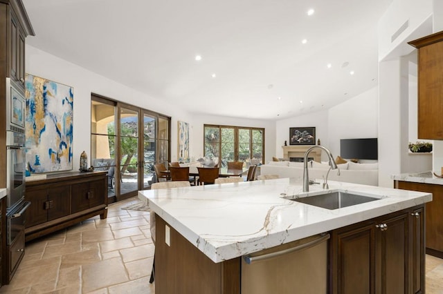 kitchen featuring light stone counters, sink, an island with sink, and appliances with stainless steel finishes