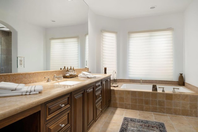 bathroom with vanity and tiled tub