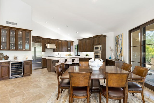 dining area with sink, beverage cooler, and high vaulted ceiling