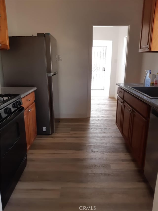 kitchen featuring dishwasher, sink, light hardwood / wood-style floors, and black gas range