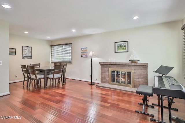 dining room with hardwood / wood-style flooring and a brick fireplace