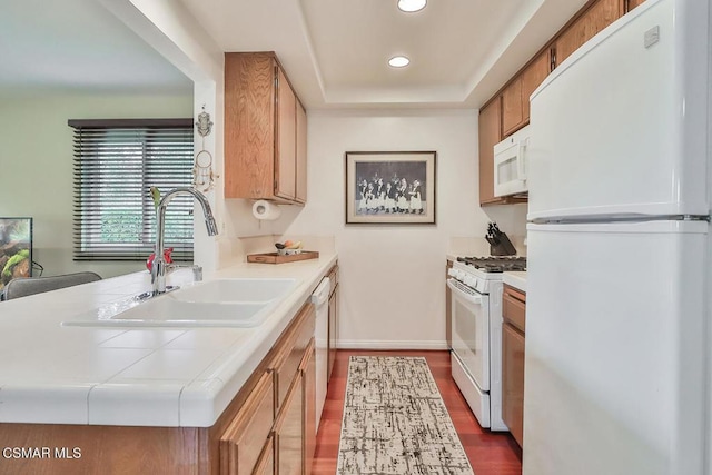 kitchen featuring a raised ceiling, dark hardwood / wood-style flooring, sink, and white appliances