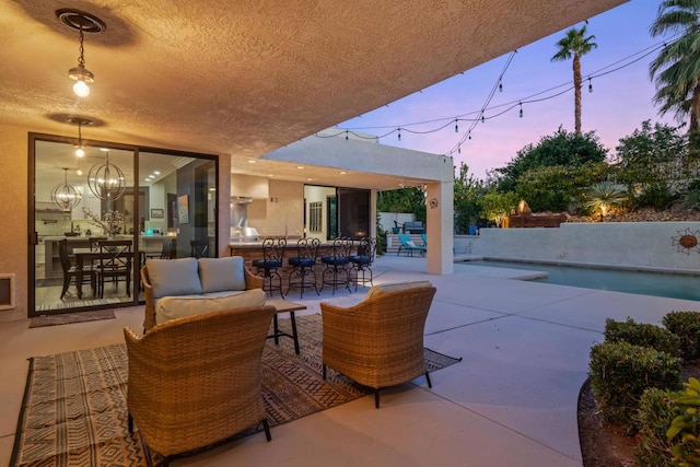 patio terrace at dusk featuring an outdoor living space and a swimming pool